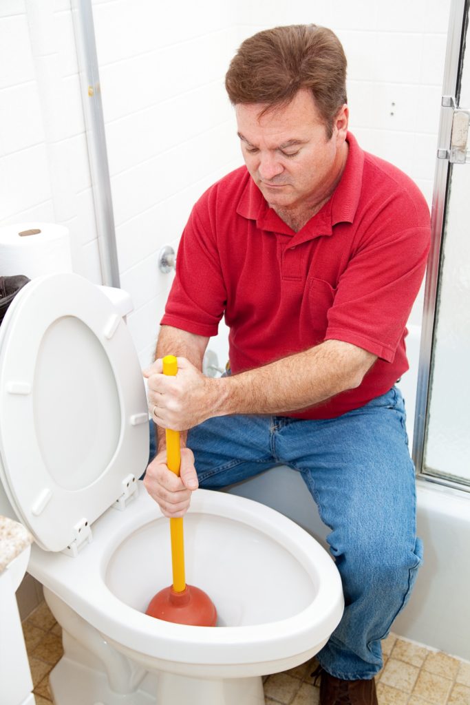plumber using a plunger to unclog a toilet