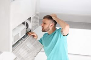 Young man fixing air conditioner at home