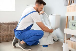 Plumber installing toilet in restroom