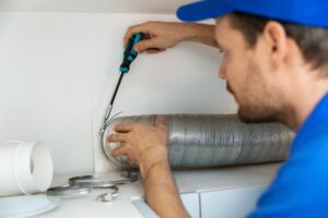 worker installing flexible aluminum ventilation tube for kitchen cooker hood exhaust system