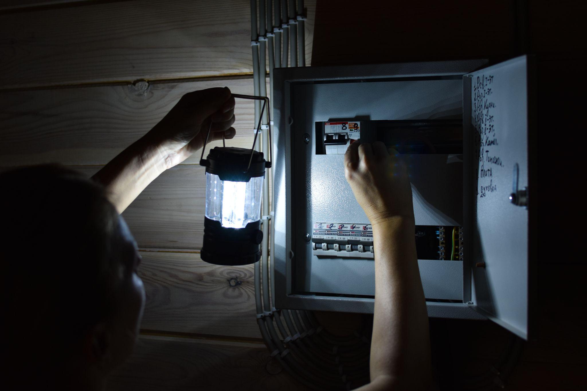 woman with flashlight looks into distribution board