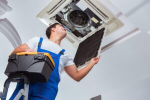 worker repairing ceiling air conditioning unit