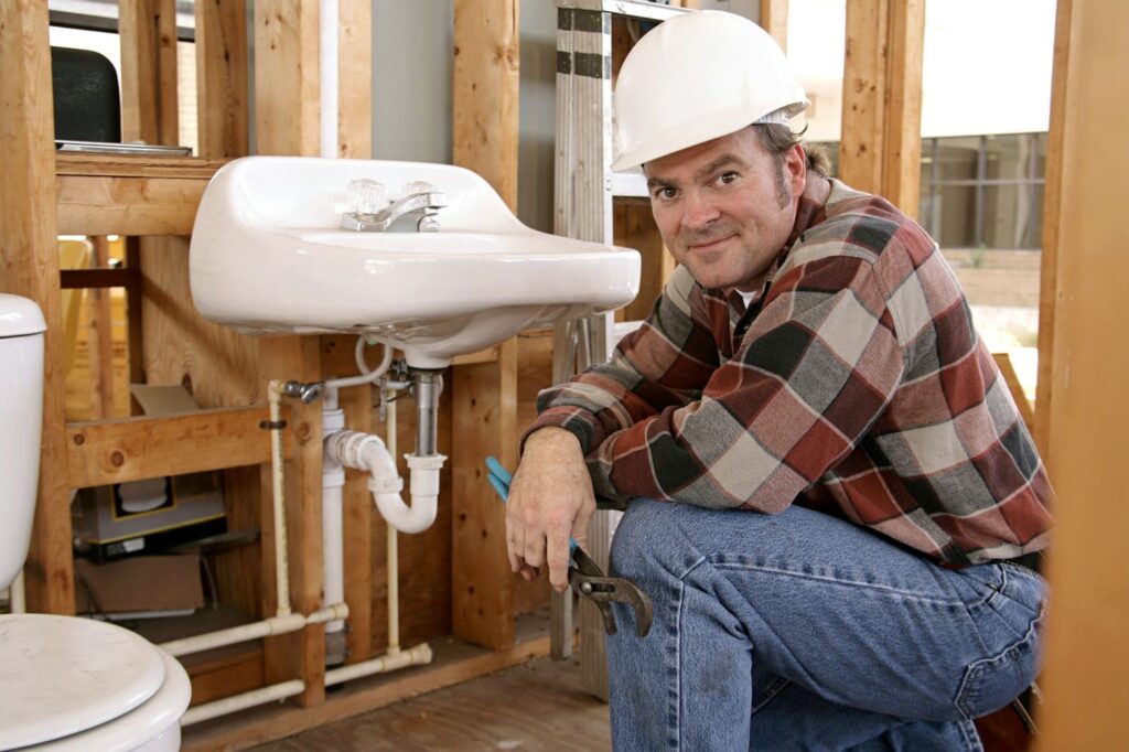 A construction plumber installing bathroom fixtures in a home under construction.