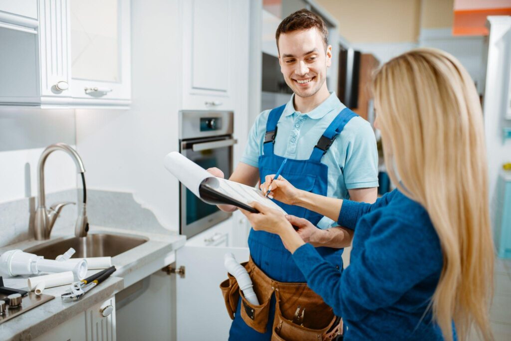 Male plumber and female customer in the kitchen