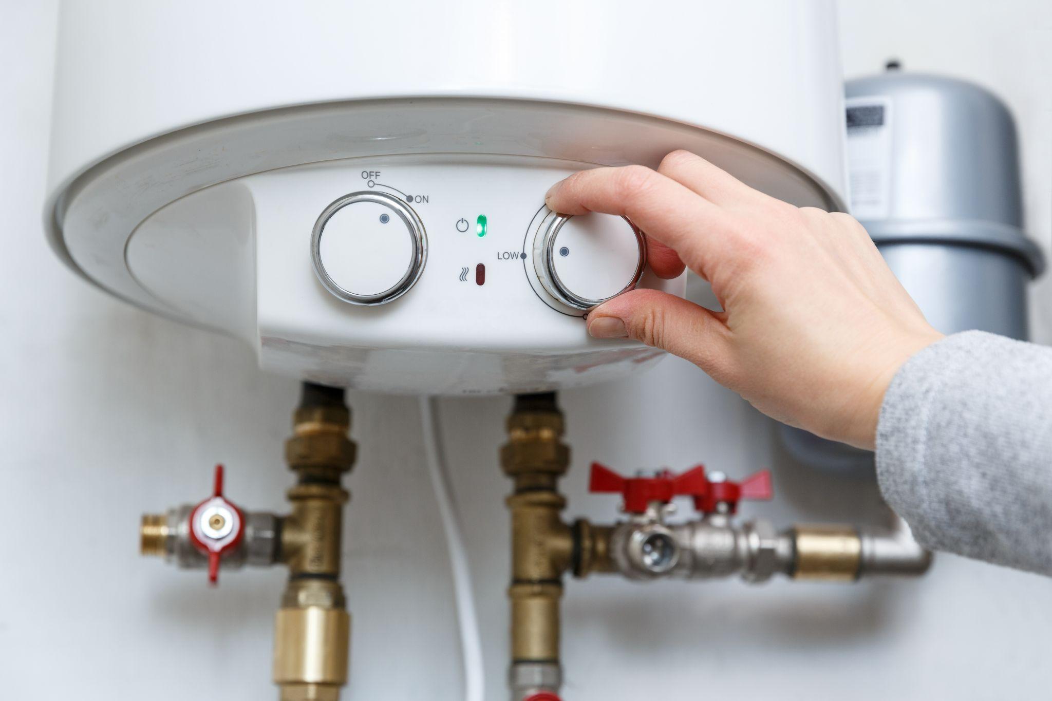 Female hand puts thermostat of electric water heater