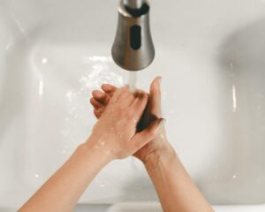 Person washing hand near white ceramic sink