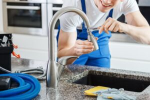 Close-up of smiling plumber fixing a faucet with blue pipes on the countertop