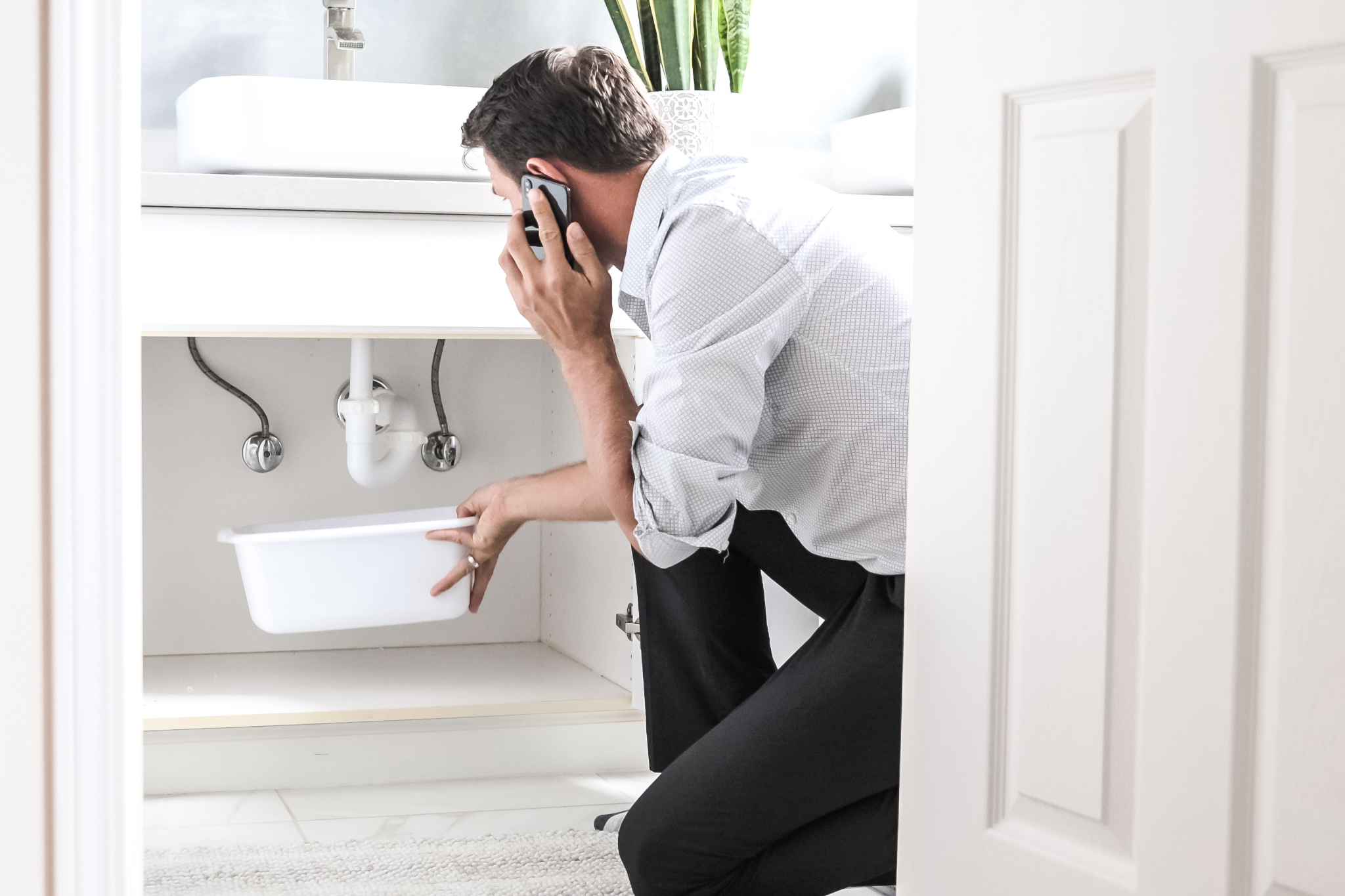 Man calling a plumber about a leaky pipe in his bathroom